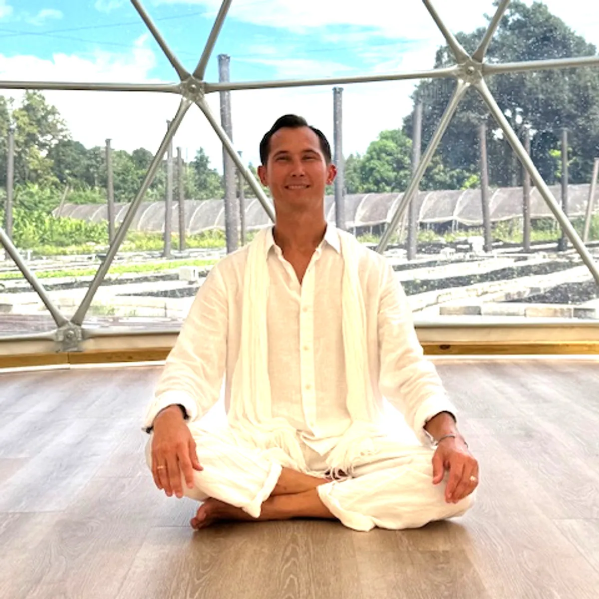 Justin Roberts, Licensed Massage Therapist and CranioSacral Diplomate, seated cross-legged in a light-filled geodesic dome
